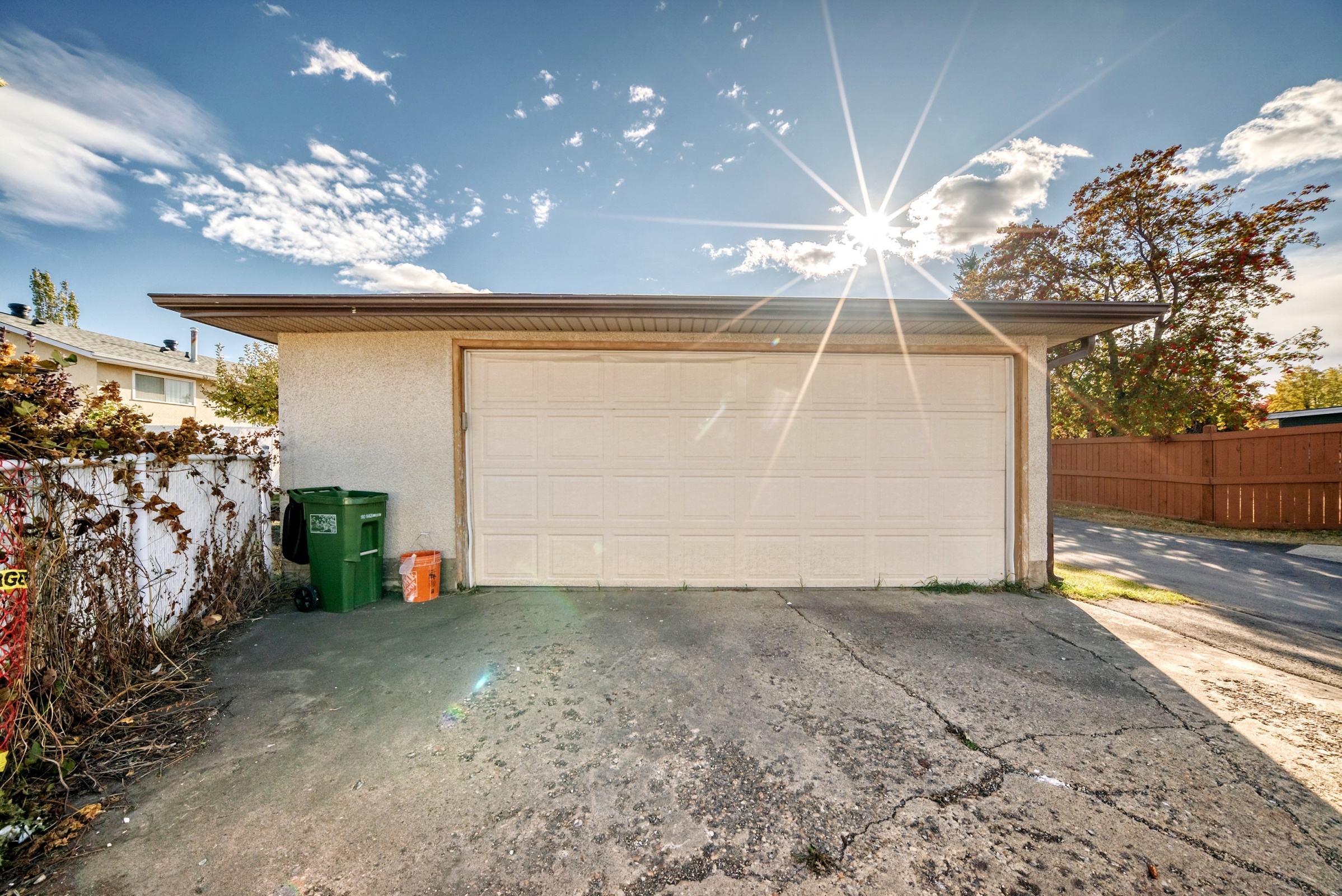 A garage with a white door is under a bright sun.